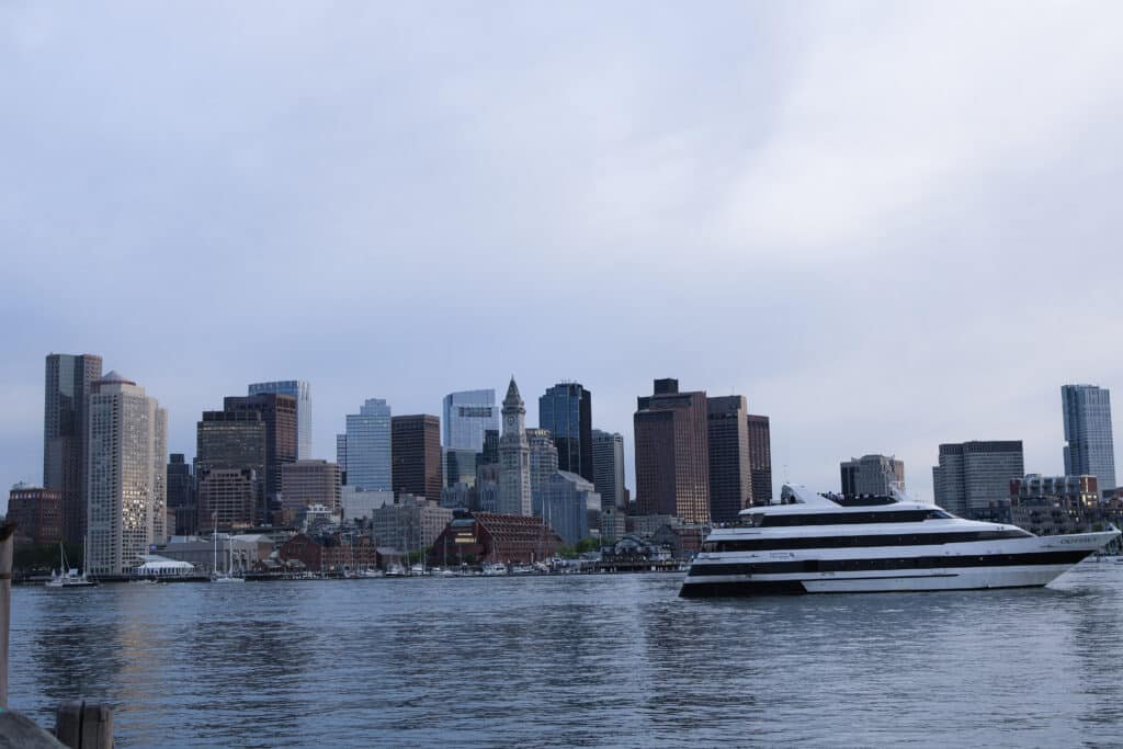 Boston Harbor skyline during the day with a passenger boat on the water.